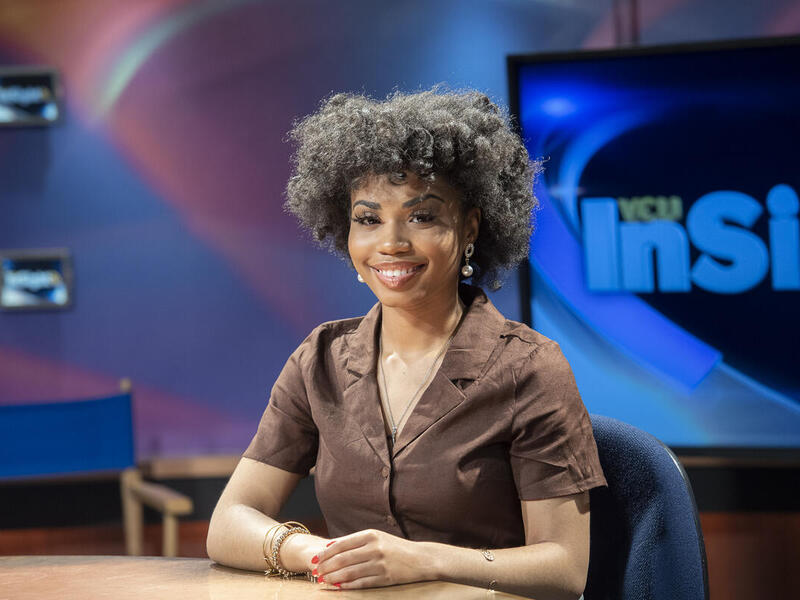 Gabriel Thomas sitting at a table with her hands resting on it.