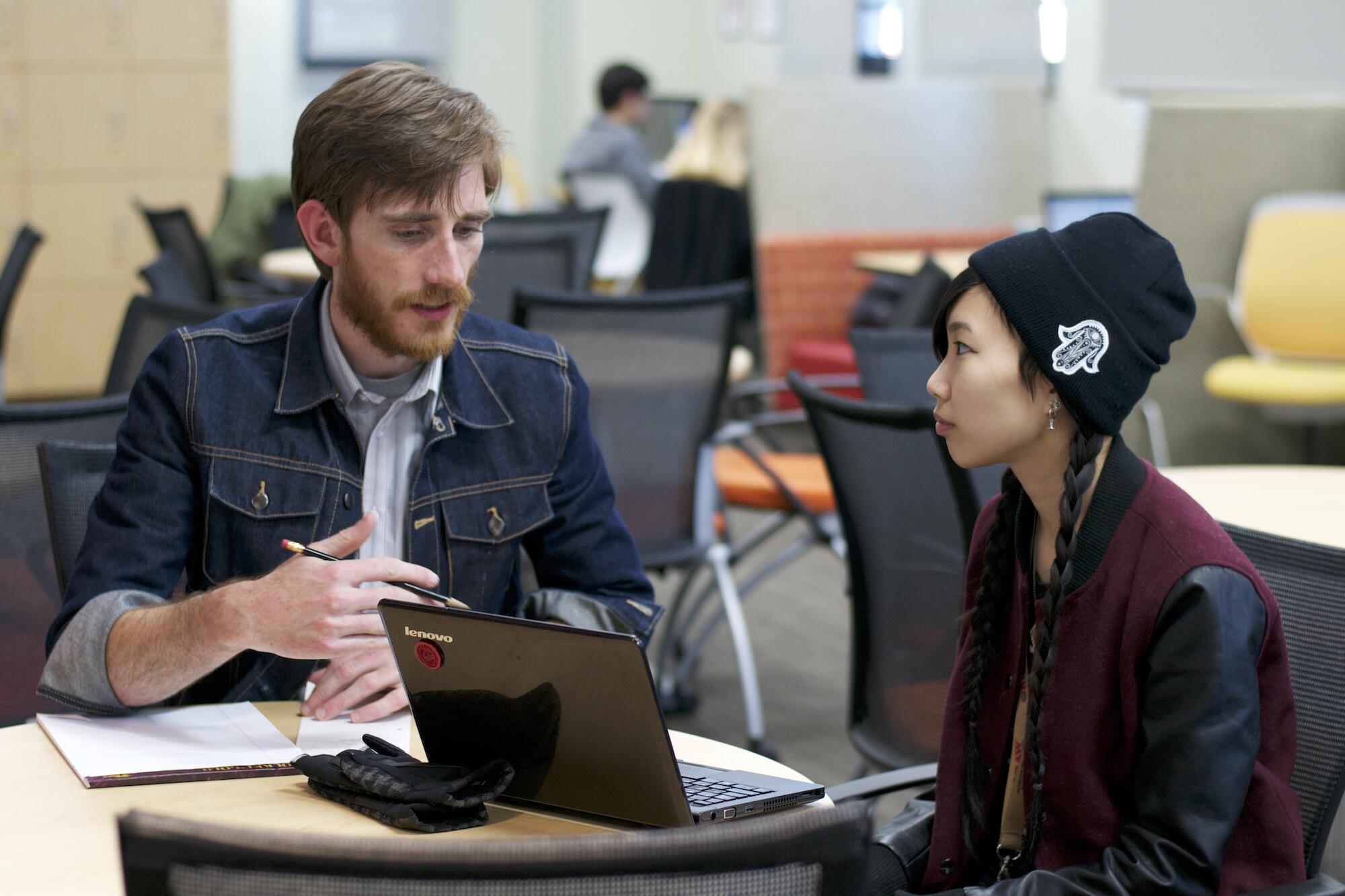 a student and a writing mentor work on a paper together