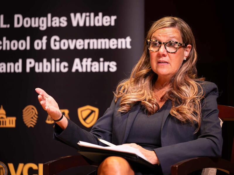 Robyn McDougle speaks at an event. Behind her are the words: L. Douglas Wilder School of Government and Public Affairs.