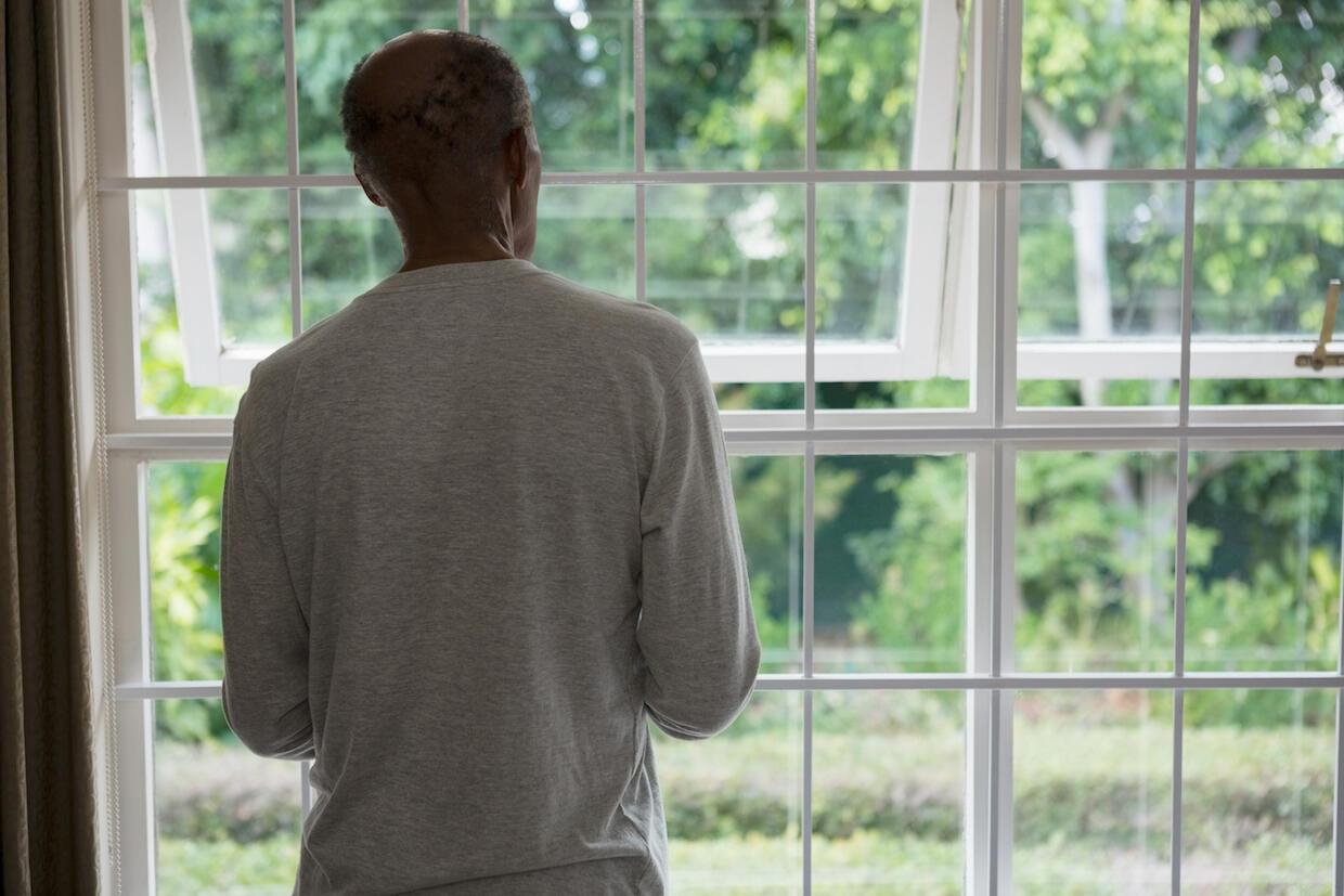 Older man peers out window. 