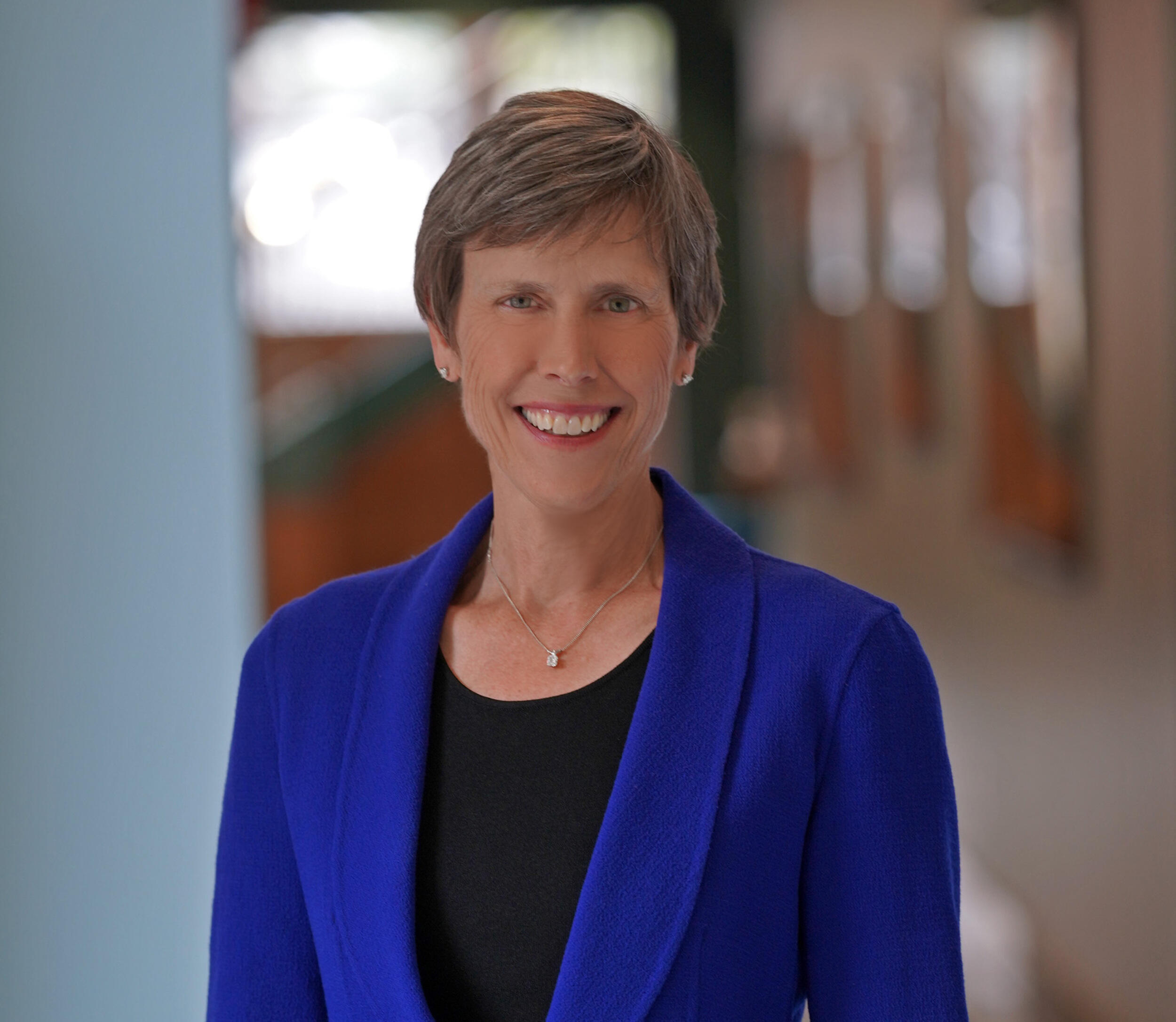 Photo of woman in blue jacket standing and smiling at the camera.