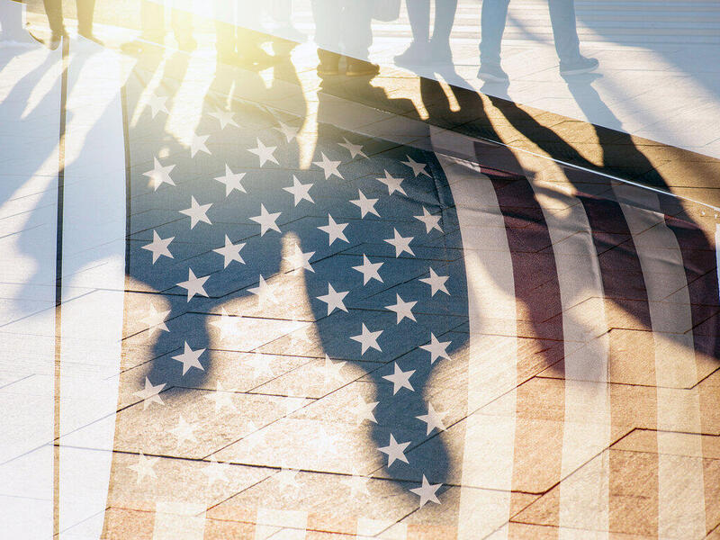 A photo of people's shadows against an American Flag 