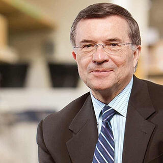 A portrait of a man wearing a sportscoat, white shirt, blue and white stripped tie, and glasses. 