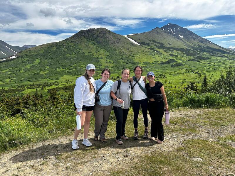 A photo of five people standing in front of mountains.