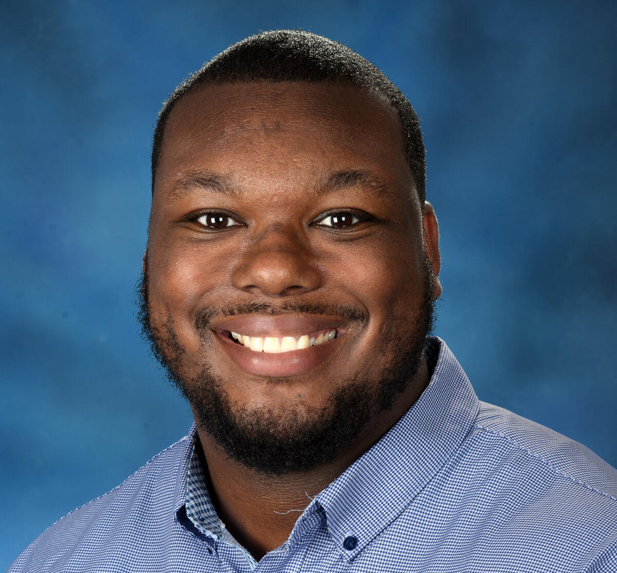 Head-and-shoulders image of a smiling man in a collared shirt.