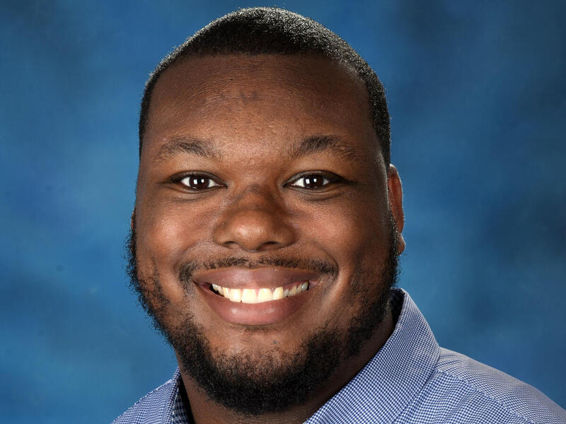 Head-and-shoulders image of a smiling man in a collared shirt.