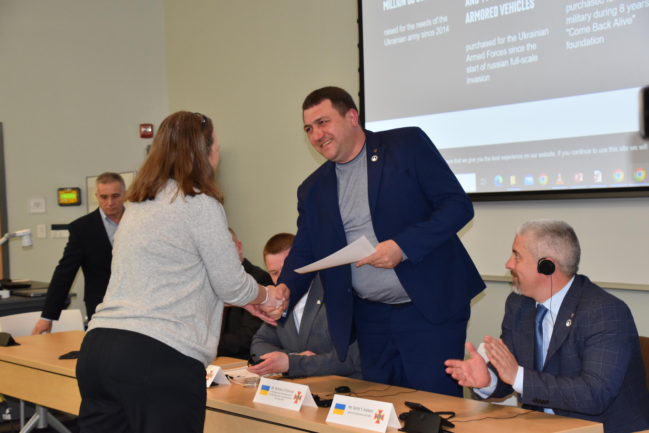 A woman shaking the hand of a man holding a piece of paper