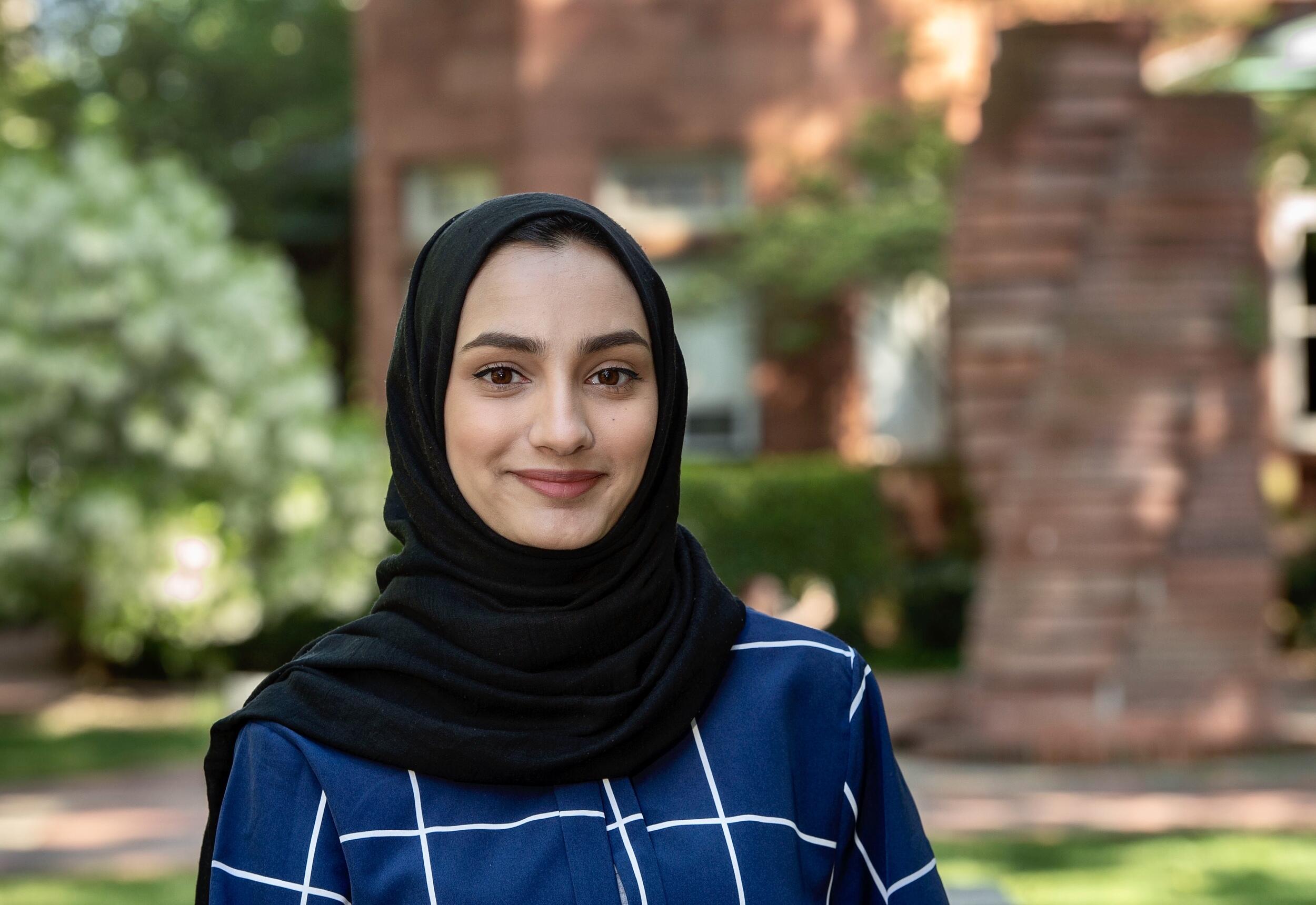 Samia Saleem wearing a black hijab and a dark blue blouse with white lines forming squares. 