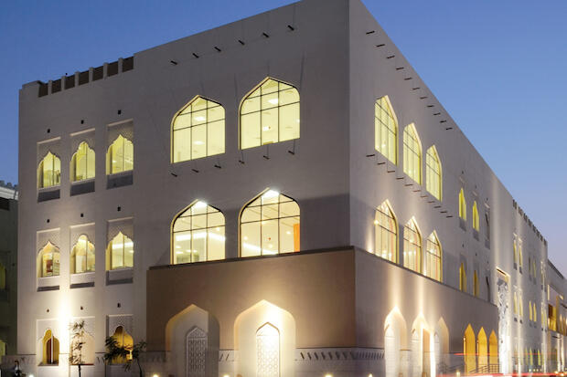 A white facade building by pictured in the evening.