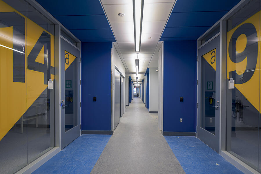 A hallway with room numbers displayed on glass walls.