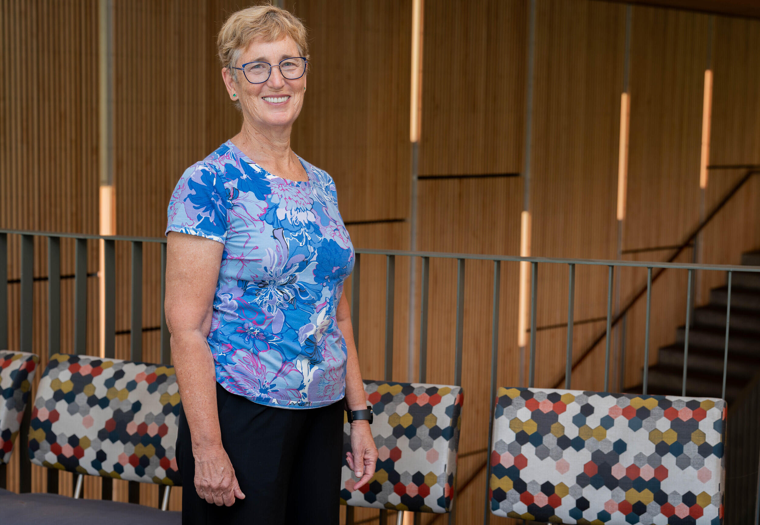 A woman stands and smiles in front of a railing.