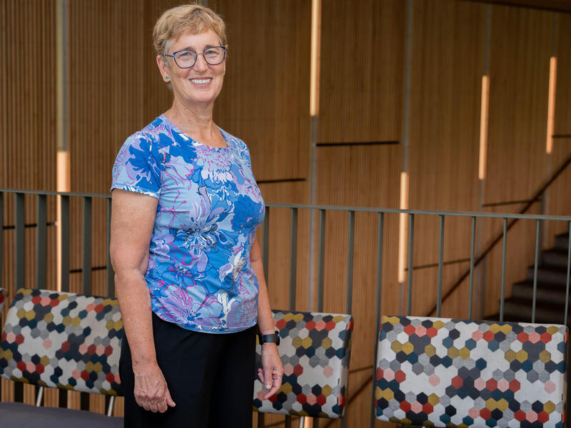 A woman stands and smiles in front of a railing.
