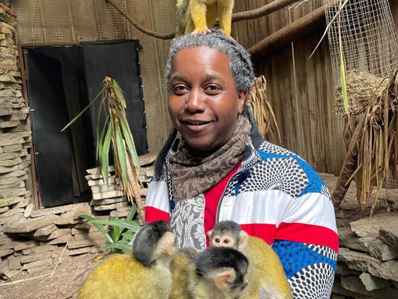 A photo of a person holding three monkeys while a fourth sits on top of their head