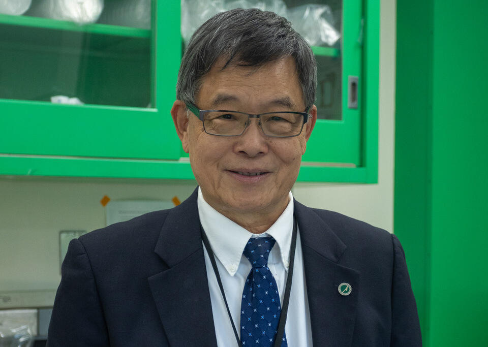 A photo of a man from the shoulders up wearing a suit, tie, button up shirt, and glasses. 