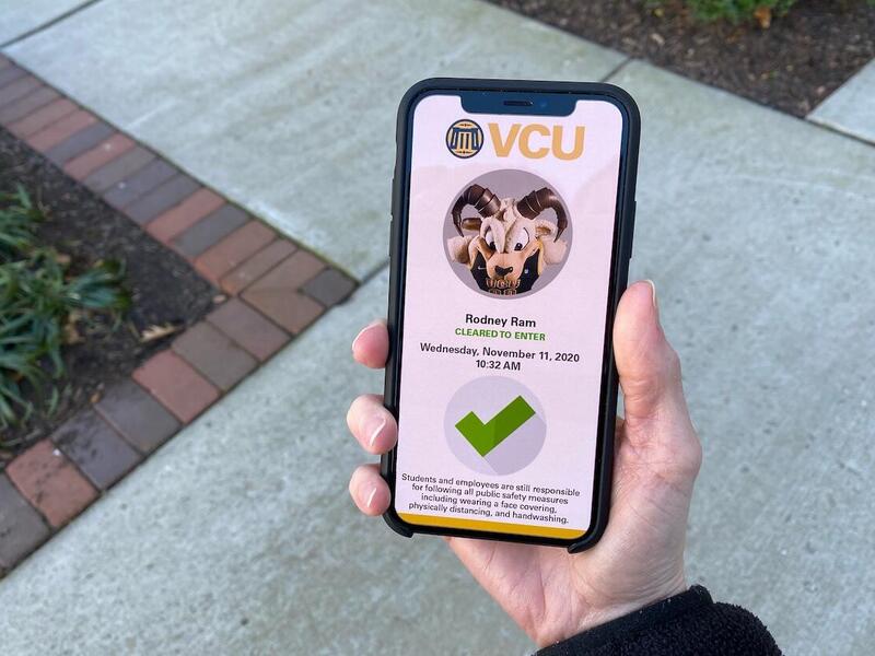 A person holding a cell phone displaying the V C U Entry Pass application with the cleared to enter screen for Rodney the Ram.
