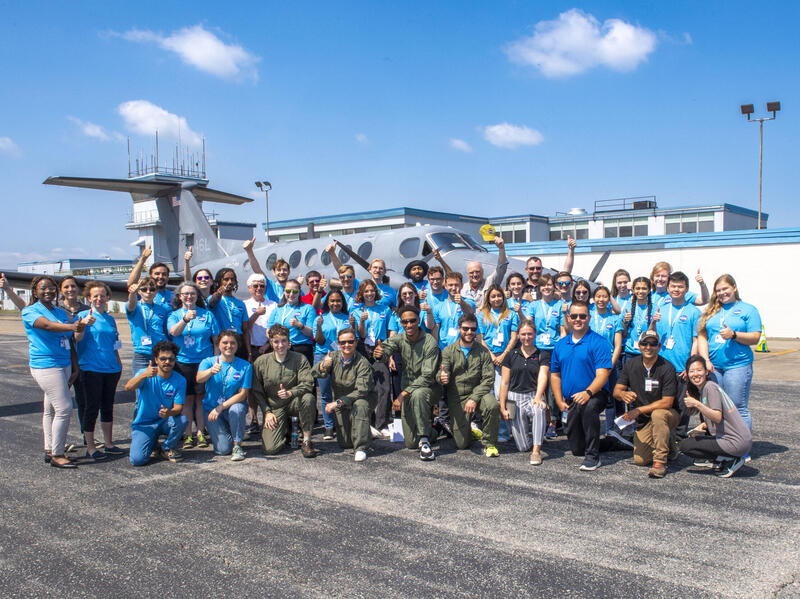 A grouple of people standing in front of an airplane at an airport