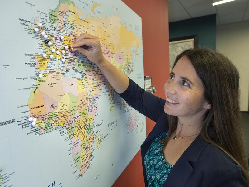 A photo of a woman putting a white pin on a map. 