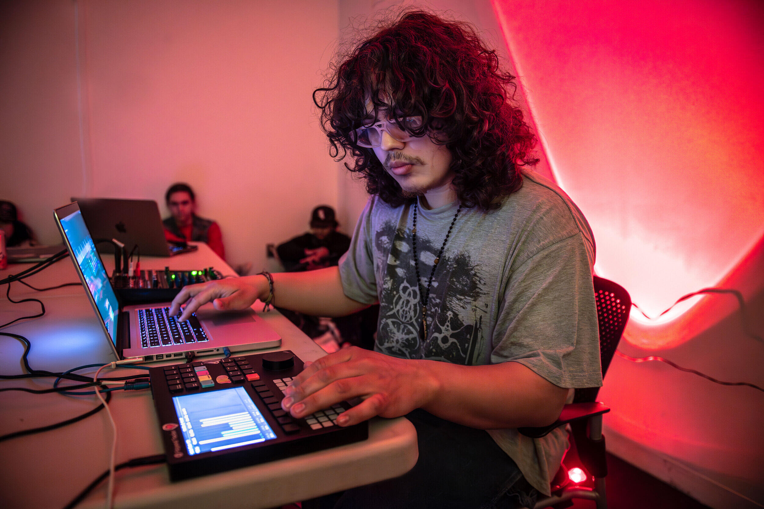 A photo of a man sittin at a table with a laptop and a soundboard. 
