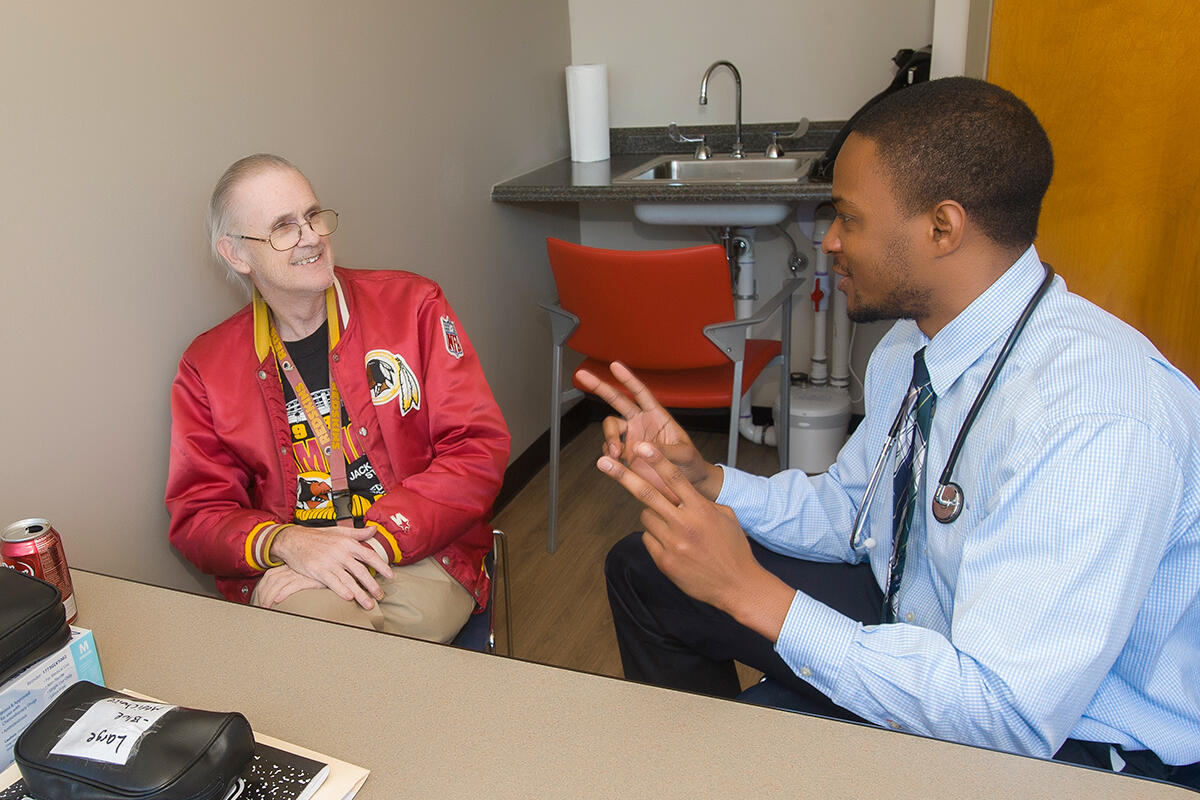 Fourth-year pharmacy student Daniel Ngembus consults with Dominion Place resident Raymond Dillard, 66, at the Richmond Health and Wellness Program. “The patients might have primary care physicians, but the means of communicating with them depends on us,” he said. “There might be disparities in their medication regimen and it’s up to us to see where the disparities lie and possibly contact their physician to update them.” 