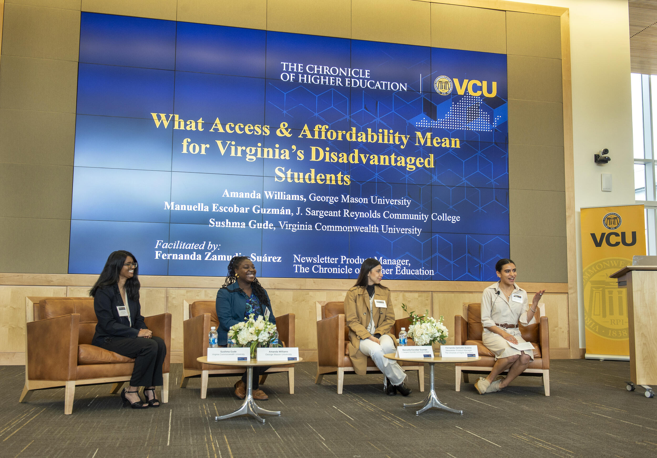 Four people sitting in chairs in front of a screen. 