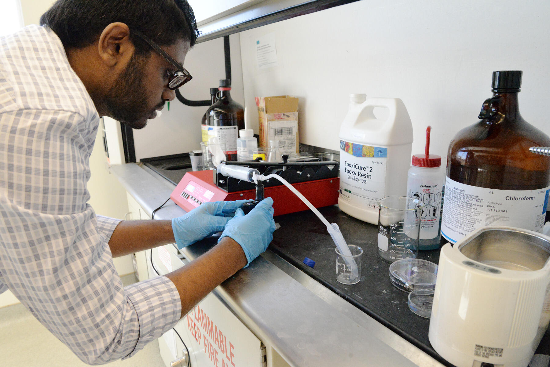 Suraj Kandalam, a biomedical engineering graduate student, works with a pump to infuse e-liquid vapor with saline to use during experimentation. The pump, which he created by modifying an apparatus that mimics smoking tobacco cigarettes, is meant to realistically simulate vaping. An atomizer heats up the e-liquid, turning it into vapor, which is then sucked through a syringe before it is infused with the saline. 
<br>Photo by Leah Small, University Public Affairs