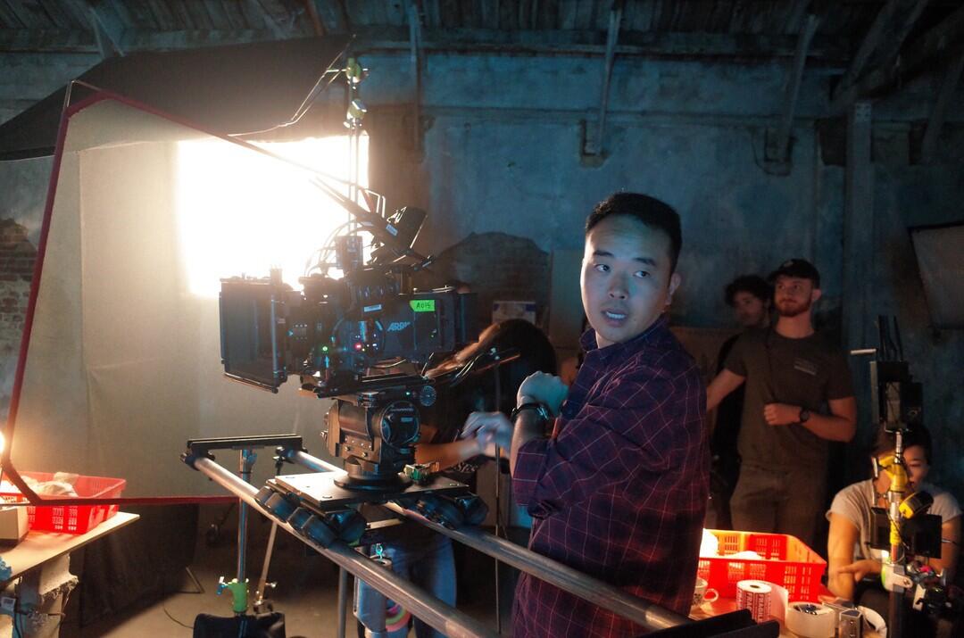 A man behind a camera on a filming set 