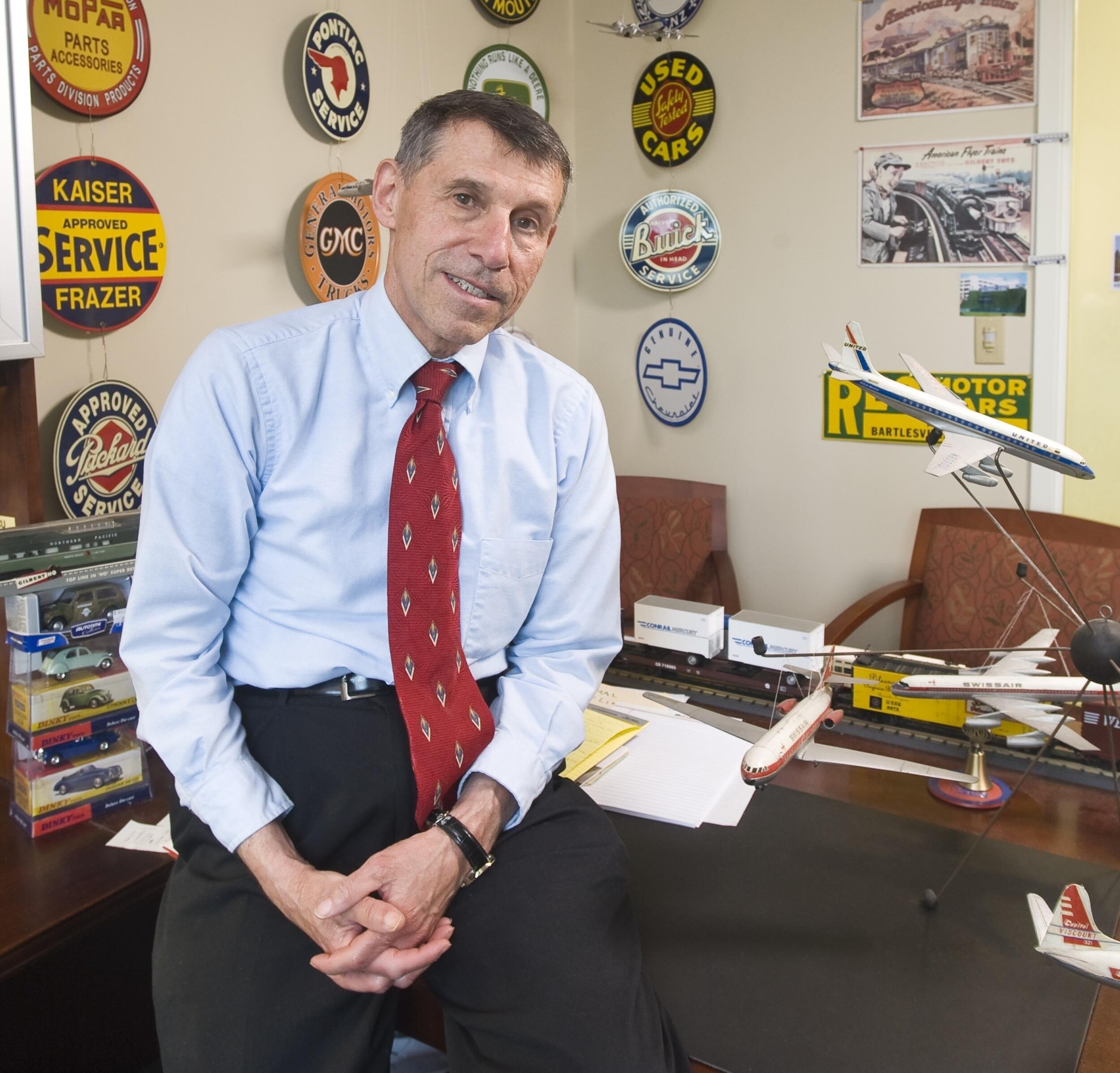 George Hoffer, Ph.D., sitting on his desk in his office