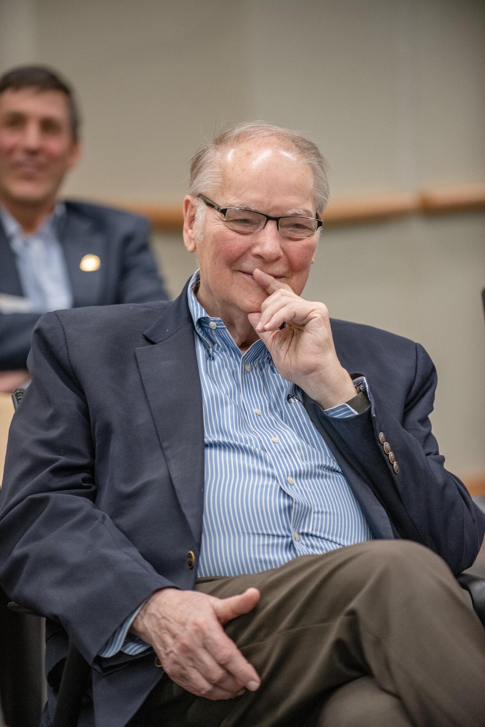 Stephen Custer, seated at a presentation and with a pensive look on his face.