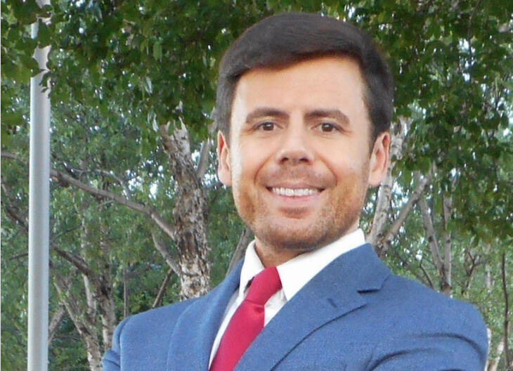 A photo of a man wearing a blue suit and a red tie