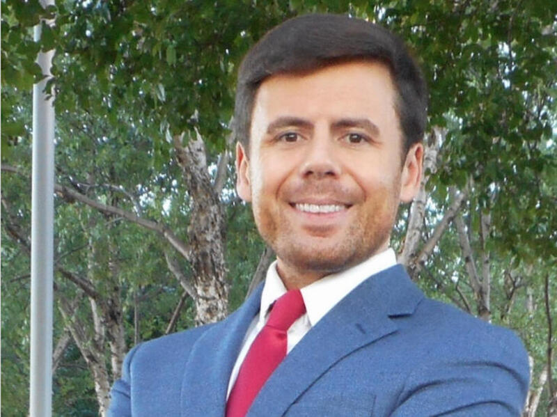 A photo of a man wearing a blue suit and a red tie