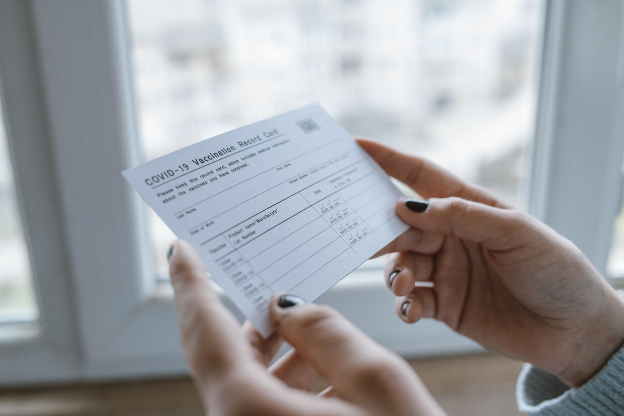 woman holding a covid-19 vaccine card