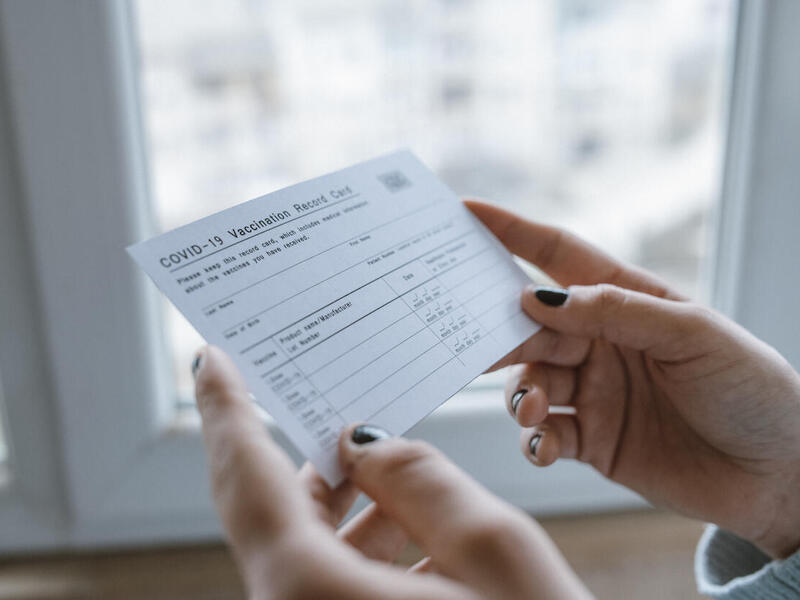 woman holding a covid-19 vaccine card