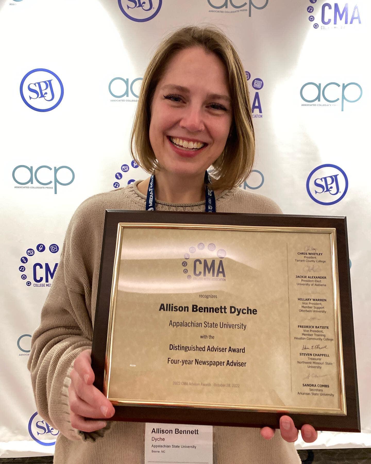 A photo of a woman holding a framed award certificate. 