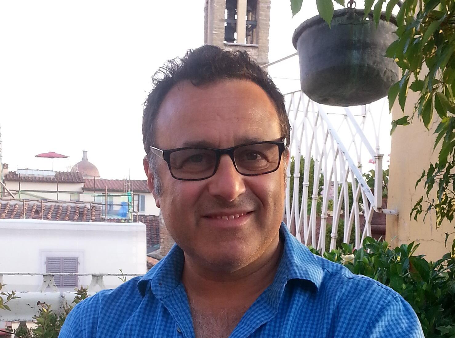 A photo of a man wearing a button up shirt and sunglasses 