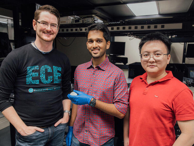 A photo of three men standing in a lab. 