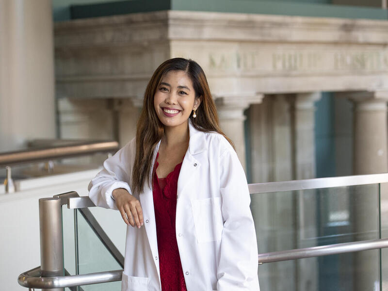 A photo of a woman smiling while wearing a white lab coat 