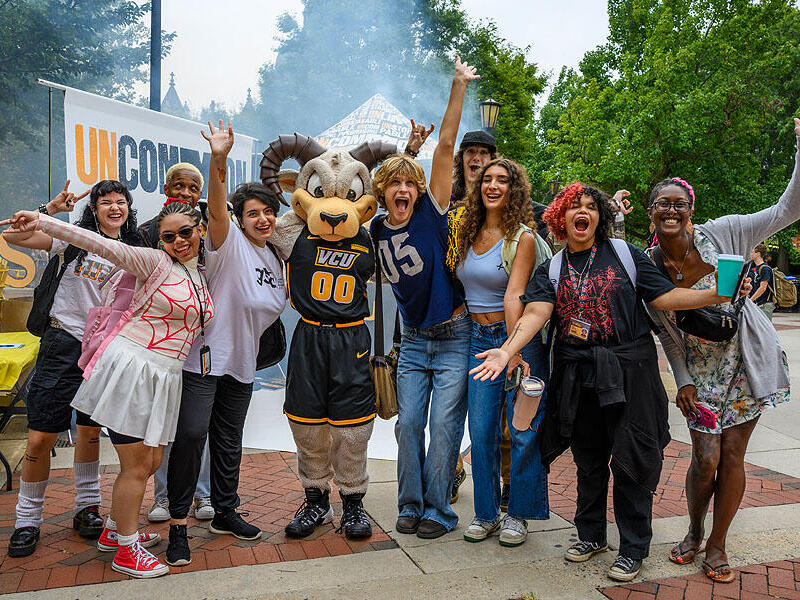 A group photo of nine people standing around Rodney the Ram. 