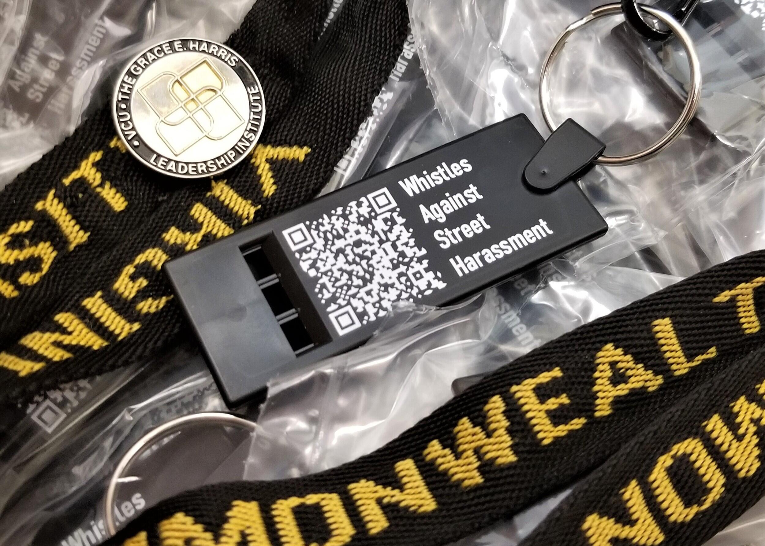 A whistle with a QR code and the text \"Whistle AGainst Street Harassment\" printed on it in white letters. 
