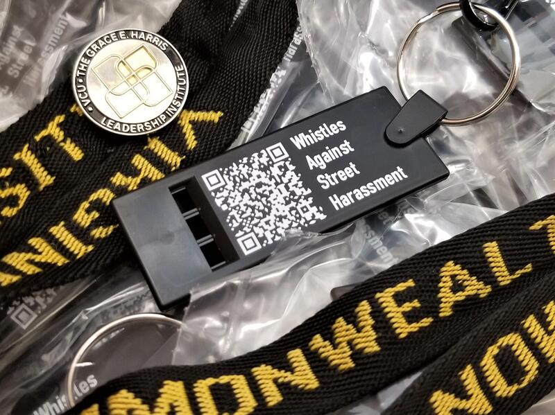 A whistle with a QR code and the text \"Whistle AGainst Street Harassment\" printed on it in white letters. 