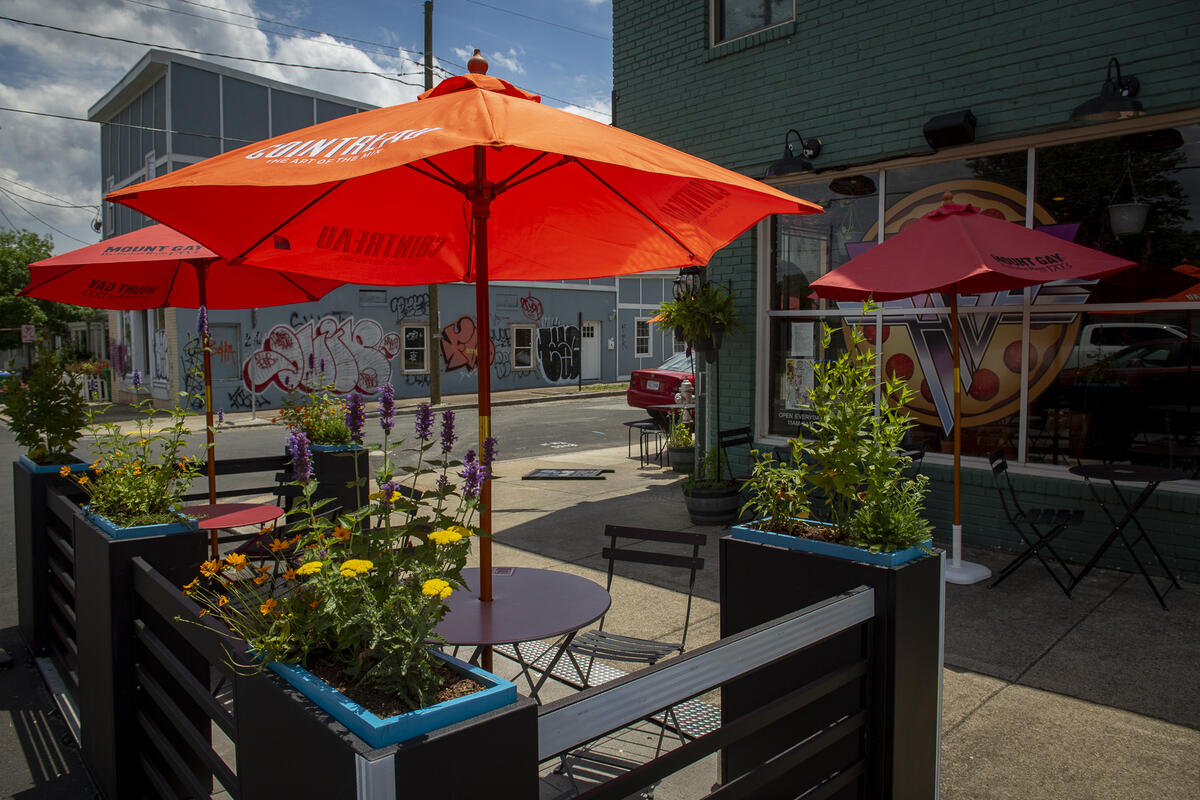 A small parklet with umbrellas, chairs and tables outside of a restaurant.