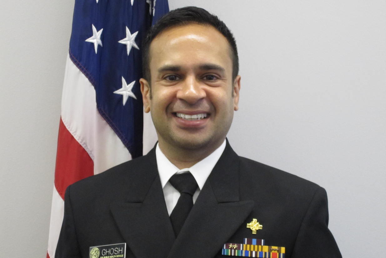 Chandak Ghosh, standing in front of an American flag, in military dress uniform.