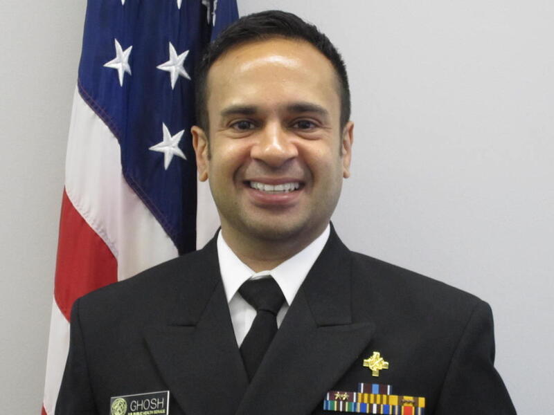 Chandak Ghosh, standing in front of an American flag, in military dress uniform.