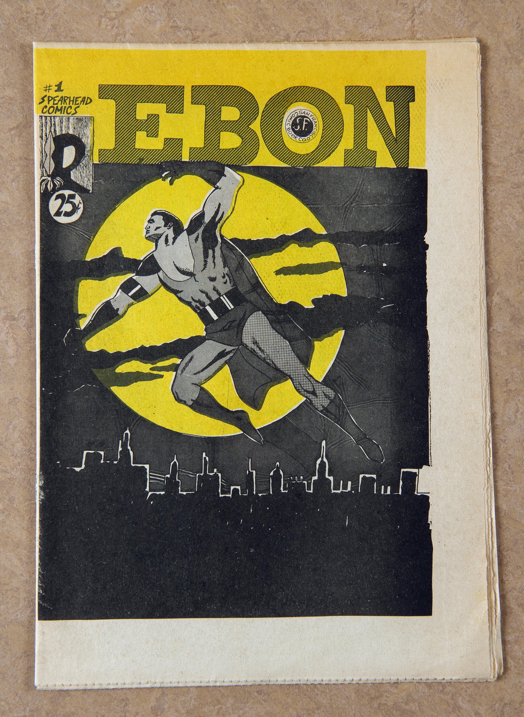A photo of a comic book with the word \"EBON\" written at the top in black text. It shows an image of a superhero wearing a costume flying over a city skyline with a full moon behind the hero. 