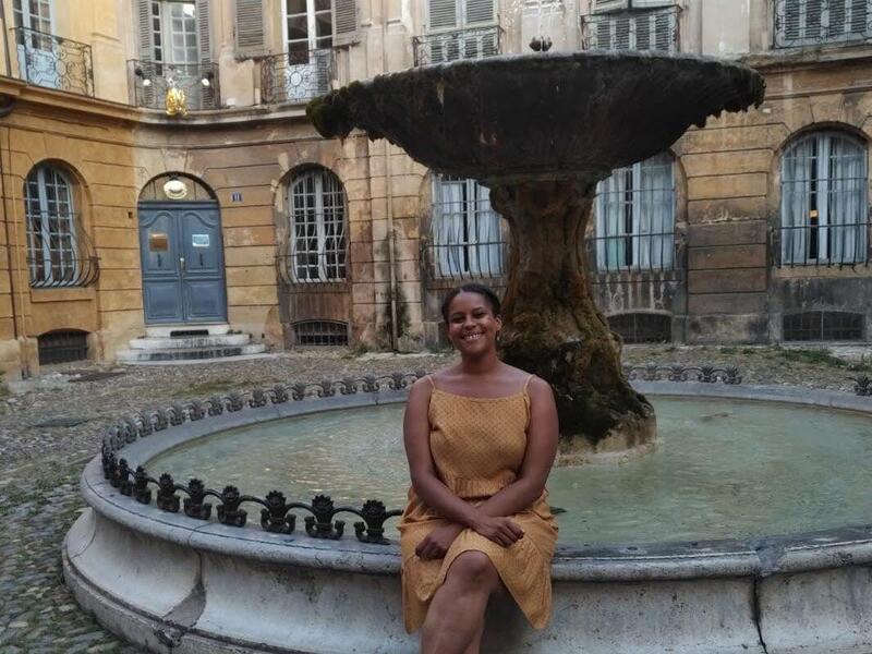 A woman sitting on the edge of a fountain. 