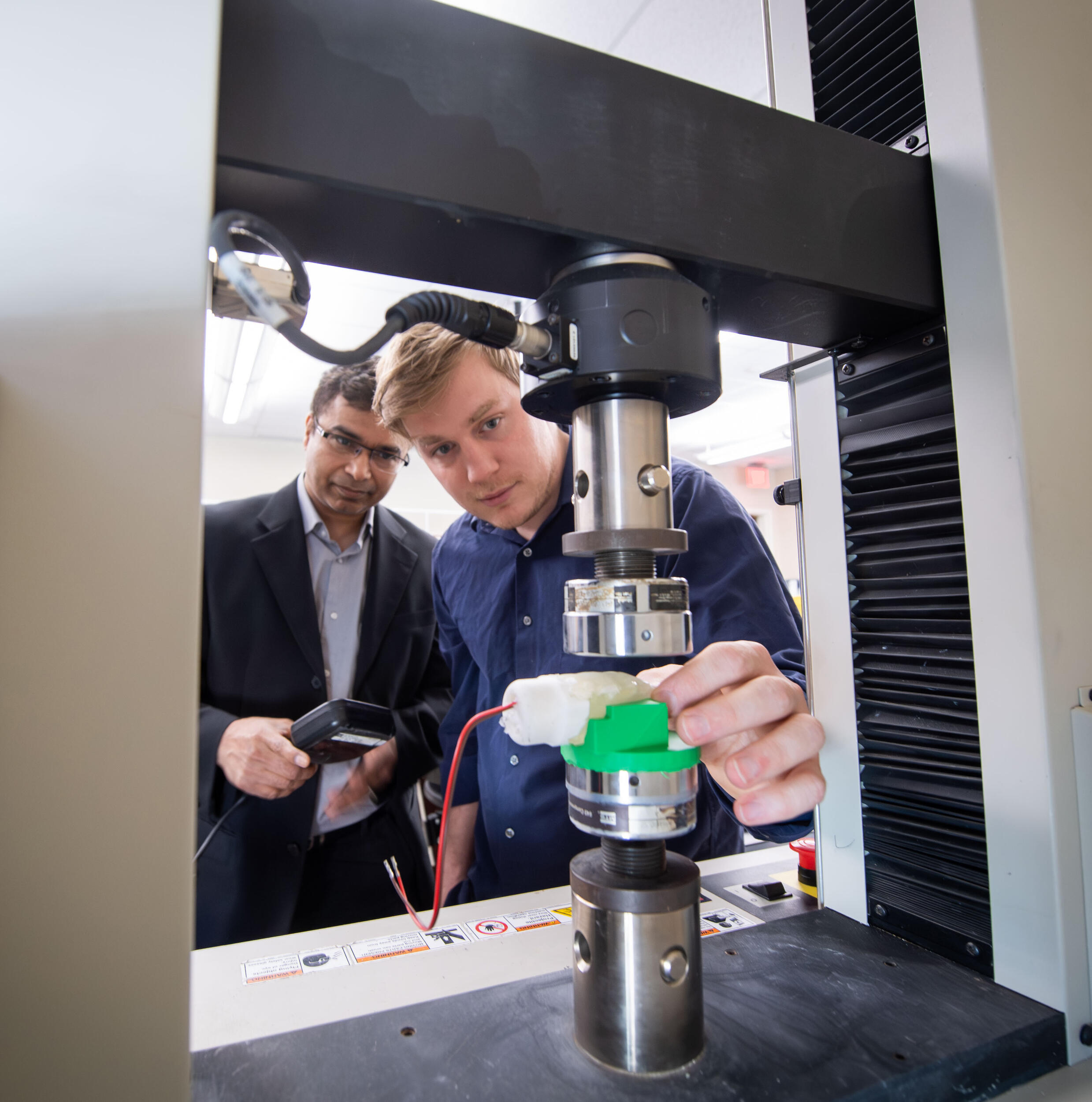 A photo of two men looking at a machine. 