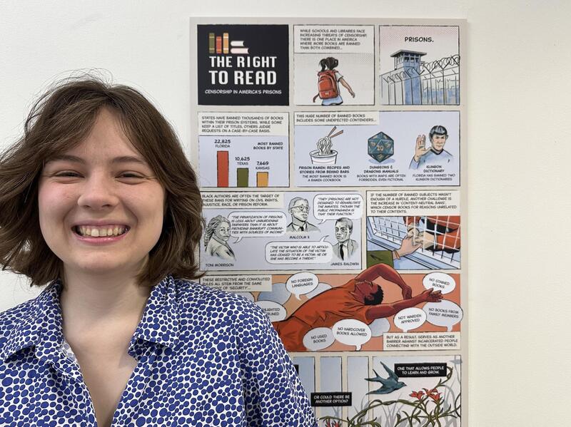 A photo of a woman smiling next to a poster with a comic on it. 