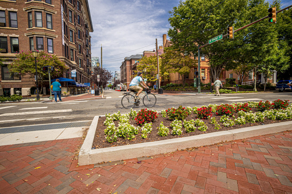 The intersection of Franklin and Shafer Street on the Virginia Commonwealth University campus. Two people are using the crosswalk on opposite sides while a bicyclist goes through the intersection. 