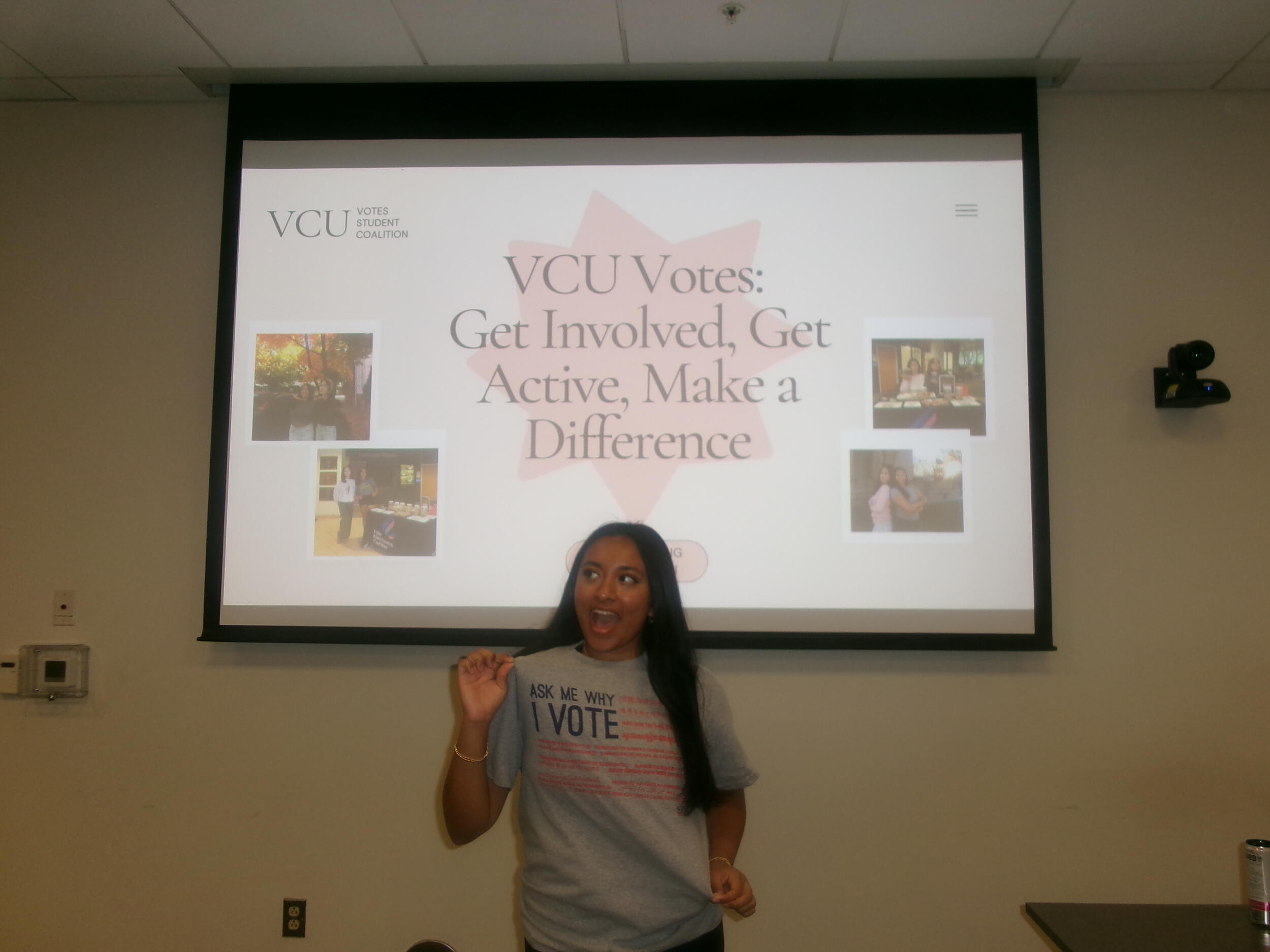 A woman standing in front of a screen with a projection that says \"VCU Votes: Get Involved, Get Active, Make a Difference\" 