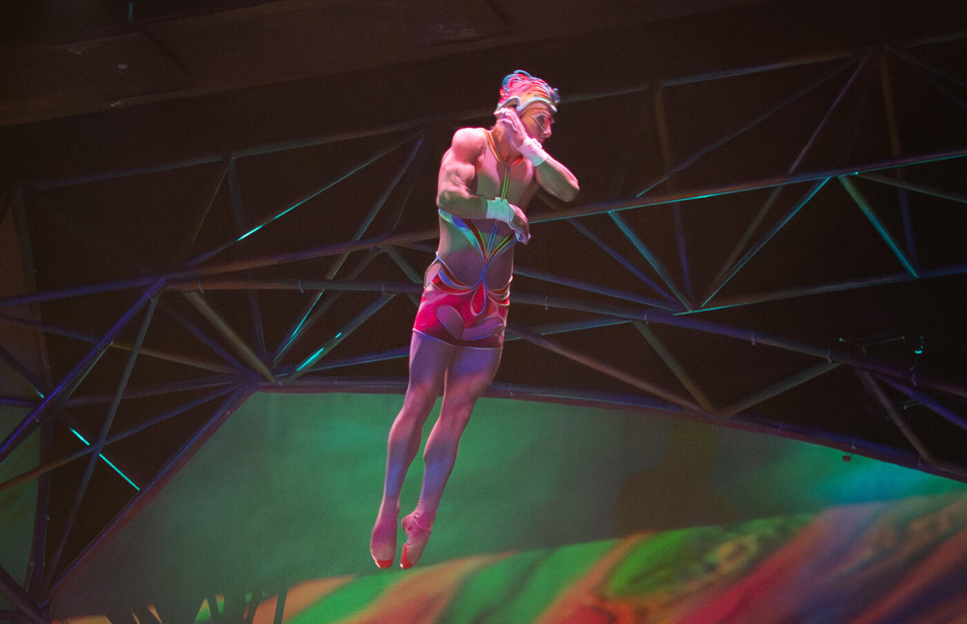 A photo of a man jumping wearing colorful shorts and a matching helmet. 
