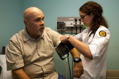 VCU medical student, Shira Goldstein, checks the blood pressure of a patient at the CrossOver Ministry clinic on Cowardin Avenue. Image courtesy of Hal Tyler Photography.